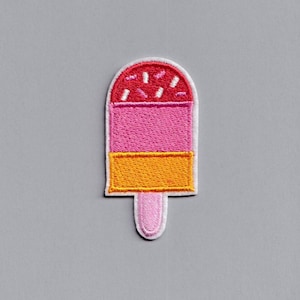 Puede incluir: Un parche bordado de helado de paleta en rosa, naranja y rojo con chispas blancas en la parte superior.