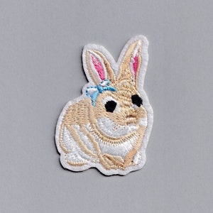 Peut inclure: Un patch brodé de lapin beige avec de la fourrure blanche, des oreilles roses et un nœud bleu. Le patch est parfait pour ajouter une touche de fantaisie aux vêtements, aux sacs ou à d'autres accessoires.