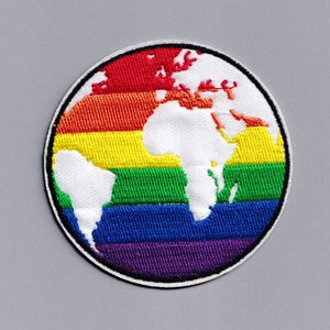 Può includere: Una toppa ricamata che raffigura un mondo bianco su uno sfondo arcobaleno.