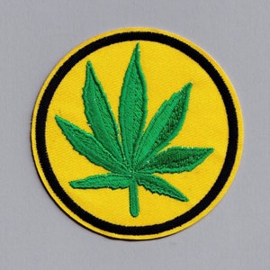 May include: A green marijuana leaf embroidered on a yellow circle with a black outline.