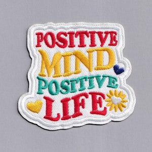 May include: White embroidered patch with the text "POSITIVE MIND POSITIVE LIFE" in colourful lettering. The patch features a heart and a sunflower.