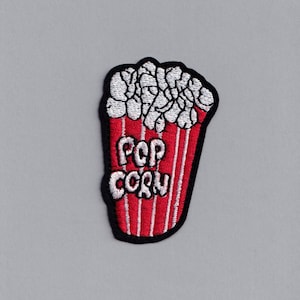 Puede incluir: Parche de hierro bordado en rojo y blanco de un cubo de palomitas de maíz con el texto "POP CORN" en la parte delantera.
