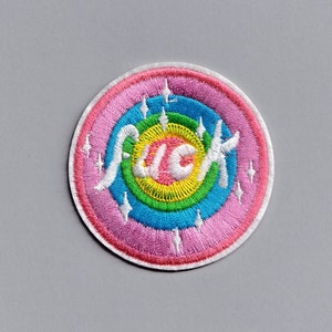 May include: A pink, rainbow, and white embroidered patch with the word "Frick" in white lettering.