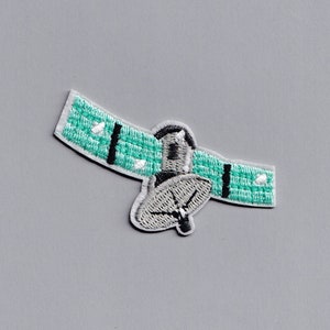 May include: Embroidered patch depicting a satellite. The patch has a light green rectangular body with white dots and black stripes. The satellite dish and central body are grey with white stitching. The patch is set against a grey background.