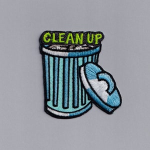 May include: Embroidered patch showing a light blue and white bin with the words "CLEAN UP" in green. The bin has a lid beside it. The patch is set against a grey background.