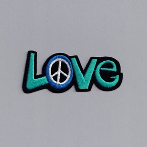 May include: A turquoise blue and black embroidered patch with the word "LOVE" and a peace sign in the centre of the "O".