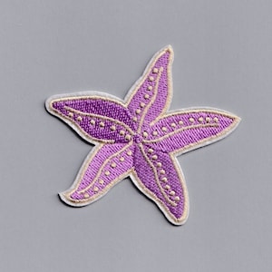 Könnte beinhalten: Lilafarbener gestickter Seestern-Patch mit weißem Rand und kleinen weißen Punkten.
