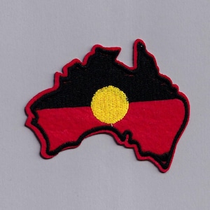 Puede incluir: Un parche bordado con la forma de Australia con el diseño de la bandera aborigen. La bandera presenta un esquema de colores negro, rojo y amarillo con un círculo amarillo en el centro.