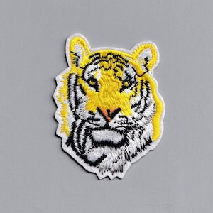 May include: An embroidered iron-on patch of a tiger's face, featuring yellow and black colours.