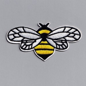 May include: An embroidered bee patch in black and white with yellow stripes. The bee has wings and a stinger.