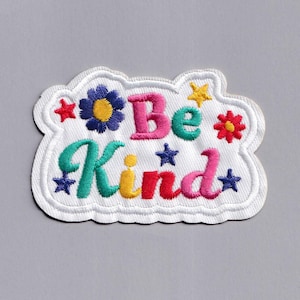 May include: White embroidered patch with the words "Be Kind" in colorful letters surrounded by stars and flowers.
