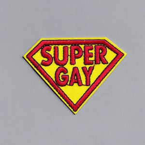 May include: A yellow and red embroidered patch shaped like a superhero logo with the text "SUPER GAY" inside.