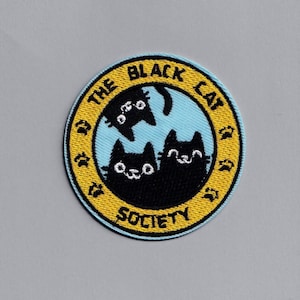 Peut inclure: Un patch brodé jaune et bleu avec le texte "The Black Cat Society" et trois chats noirs à l'intérieur du cercle.