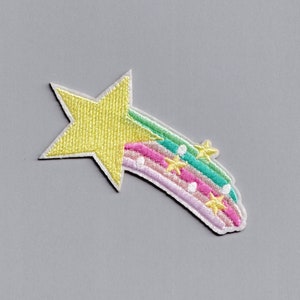 Könnte beinhalten: Ein gelber Stern mit einem Regenbogen-Schwanz und weißen Punkten. Der Regenbogen ist rosa, grün und blau. Auf dem Schwanz sind kleine gelbe Sterne.