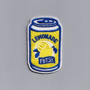 Puede incluir: Un parche bordado de una lata amarilla de limonada con una rodaja de limón y las palabras "LEMONADE" y "FRESH" en él.