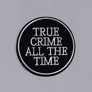 Op de afbeelding: Een geborduurde zwarte en witte patch met de tekst "TRUE CRIME ALL THE TIME" in een cirkel.