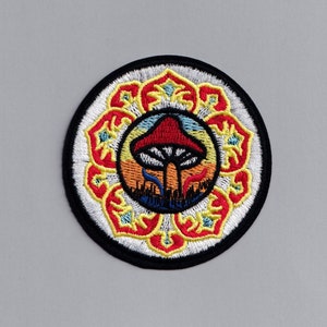 May include: Embroidered patch with a colourful mandala design featuring a red and white mushroom in the centre. The mushroom is surrounded by a sunset-like background with yellow, orange, and blue hues.