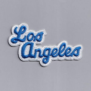 May include: Blue and white embroidered patch with the text "Los Angeles" in a cursive font.