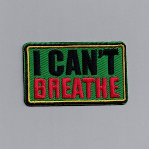 Könnte beinhalten: Ein rechteckiger Aufnäher mit den Worten "I CAN'T BREATHE" in Schwarz und Rot auf grünem Hintergrund gestickt. Der Aufnäher hat einen schwarzen Rand mit gelber Umrandung.