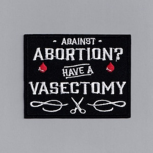 Op de afbeelding: Zwart-witte geborduurde patch met de tekst "Against Abortion? Have a Vasectomy" en twee rode bloeddruppels. De tekst is in een vetgedrukt, gestileerd lettertype. De patch heeft een decoratieve rand met twee scharen.