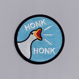 May include: A blue and white embroidered patch with a goose honking and the word "HONK" written twice.