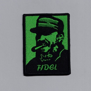 May include: Green embroidered patch with a black silhouette of a man wearing a hat and smoking a cigar. The text "FIDEL" is embroidered in green below the silhouette.
