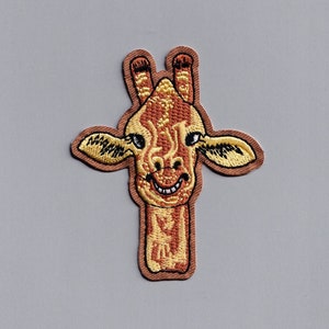 May include: Embroidered iron-on patch of a smiling giraffe with brown and yellow fur. The giraffe's head and neck are visible, with a friendly expression.