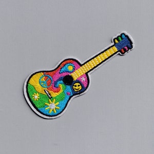 May include: A colorful embroidered patch of a guitar with peace signs, smiley faces, and suns. The guitar is yellow, pink, blue, green, and orange.