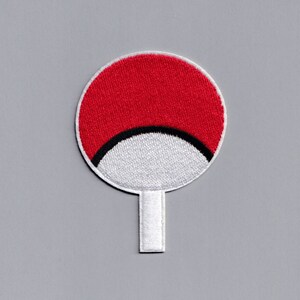 Könnte beinhalten: Roter und weißer gestickter Aufnäher mit einer schwarzen Halbmondform. Der Aufnäher ist an einem weißen Stiel befestigt.