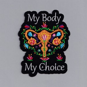 May include: Black embroidered patch with a colorful floral design surrounding a stylized uterus. The text "My Body My Choice" is embroidered in white on the patch.