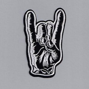 Może przedstawiać: Czarno-biała haftowana naszywka z ręką wykonującą gest rock and roll.