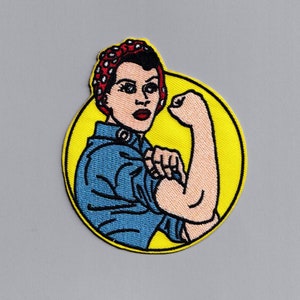 May include: A yellow circle with a red, white, and blue bandana-wearing woman with a blue shirt flexing her bicep. The woman is depicted in a vintage style.