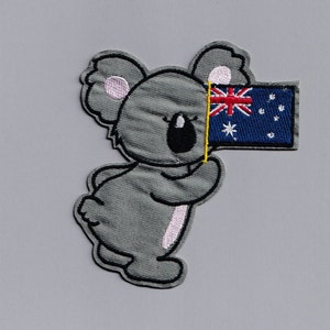 May include: A gray koala holding an Australian flag. The flag is blue with a white star and a red cross with a white background.