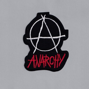 Puede incluir: Parche bordado en negro y rojo con un símbolo de anarquía blanco y la palabra "Anarquía" en rojo.