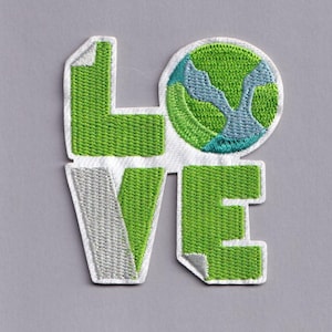 Op de afbeelding: Geborduurde patch met het woord "LOVE" in groen en grijs. De "O" is een groene en blauwe aardegrafiek. De patch staat op een witte achtergrond.