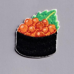 May include: Embroidered patch featuring a sushi roll with bright orange roe, a black seaweed wrap, and a green leaf garnish. The patch has a white border and is set against a gray background. This patch is perfect for adding to clothing or accessories.