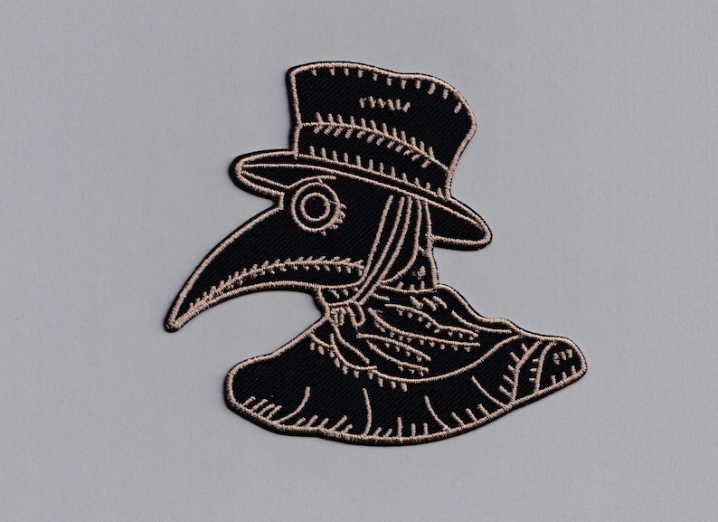 May include: Black and white embroidered patch of a plague doctor wearing a hat and a long beak mask.