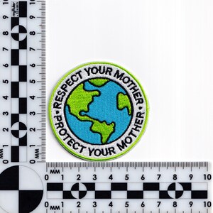 May include: A white, green and blue embroidered patch with a globe in the centre and the text "Respect Your Mother * Protect Your Mother" around the globe.