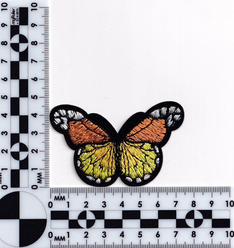 May include: A yellow and orange embroidered butterfly patch with black outlines. The butterfly has white accents on the wings.