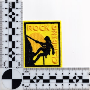 May include: Yellow embroidered patch with black stitching. The patch features a silhouette of a person rock climbing with the words "ROCK CLIMBING" in yellow.
