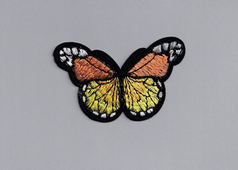 May include: A yellow and orange embroidered butterfly patch with black outlines and white accents.