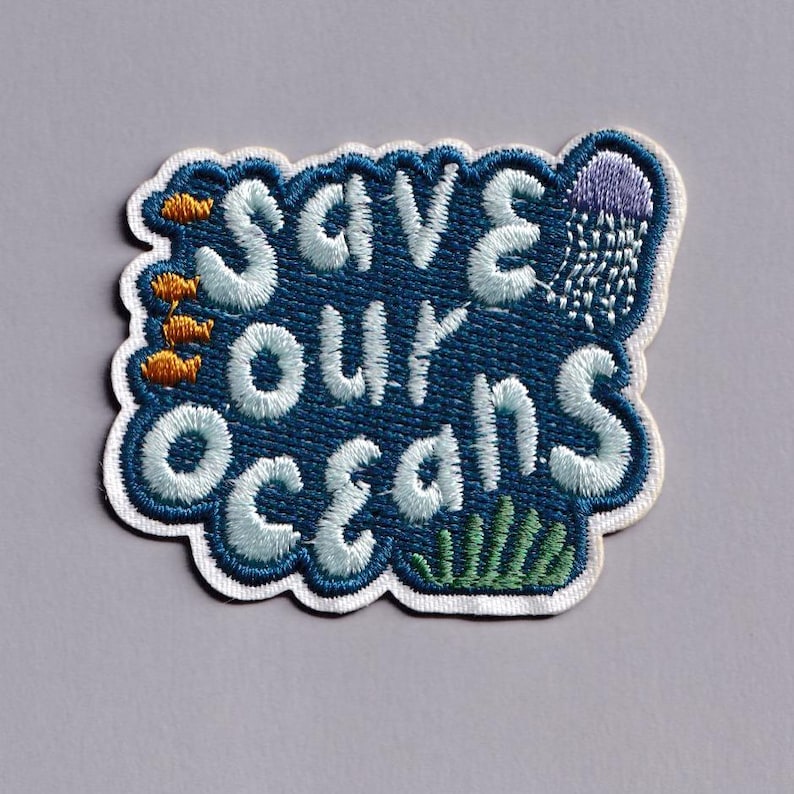 Pu&ograve; includere: Toppa ricamata con le parole "Save Our Oceans" in bianco, bordate di blu. La toppa presenta pesci arancioni, una medusa viola e alghe verdi. La toppa ha un bordo bianco.