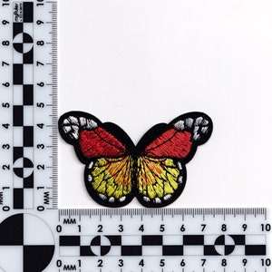 Puede incluir: Un parche de mariposa bordado en rojo y amarillo con contornos negros. La mariposa mide aproximadamente 3 cm de ancho.