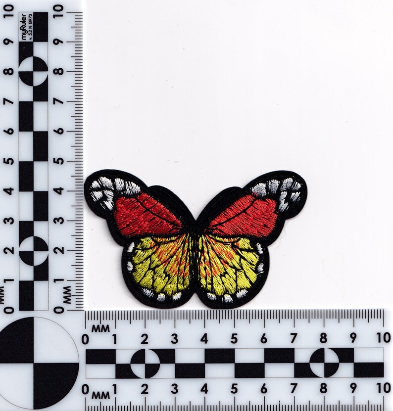 Puede incluir: Un parche de mariposa bordado en rojo y amarillo con contornos negros. La mariposa mide aproximadamente 3 cm de ancho.
