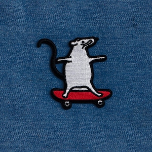 May include: Embroidered patch featuring a white rat skateboarding on a red skateboard. The rat has a black tail and is outlined in black. The patch is on a blue denim background.