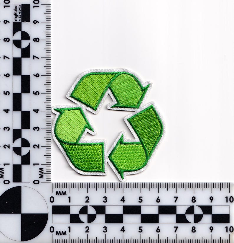 May include: A green embroidered patch featuring the universal recycling symbol, a triangle of three chasing arrows. The patch has a white border and is set against a white background. The patch is approximately 2 inches in diameter.