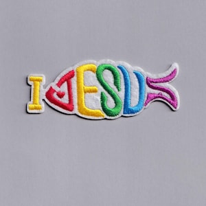 May include: Embroidered patch in the shape of a fish, with the words "I JESUS" in rainbow colors. The patch has a white border and is set against a gray background. The letters are yellow, red, yellow, green, blue, and purple.