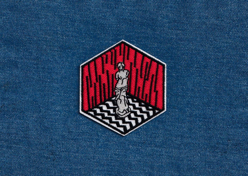 May include: A red and black embroidered patch featuring a white silhouette of a person standing in a room with a black and white checkered floor. The text "C.A.C.H.E.R." is embroidered in black on the red walls.