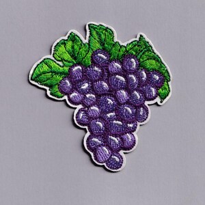 May include: Embroidered patch depicting a bunch of purple grapes with green leaves. The grapes are a deep purple, and the leaves are a vibrant green. The patch has a white border against a grey background.