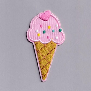 May include: Embroidered ice cream cone patch featuring a pink scoop, a yellow waffle cone, and colourful sprinkles. The pink scoop has a small pink heart on top. The patch is designed for sewing or ironing onto fabric.